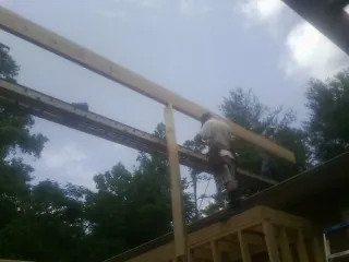 Carpenter setting a ridge beam over a new addition frame — Ice Dam Removal by Roofing Brothers in Dripping Springs