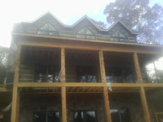 Dormers and porch framing on a large log home under construction — Roof Coating work by our crew in Dripping Springs