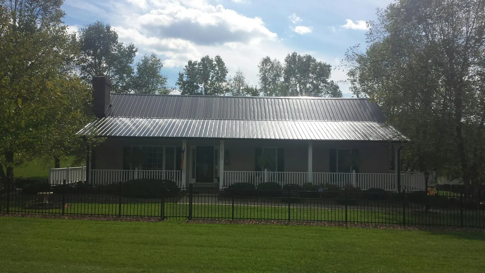 Gray metal roof on a brick ranch with a full width front porch — Gutter Guard Installation work by our crew in Dripping Springs