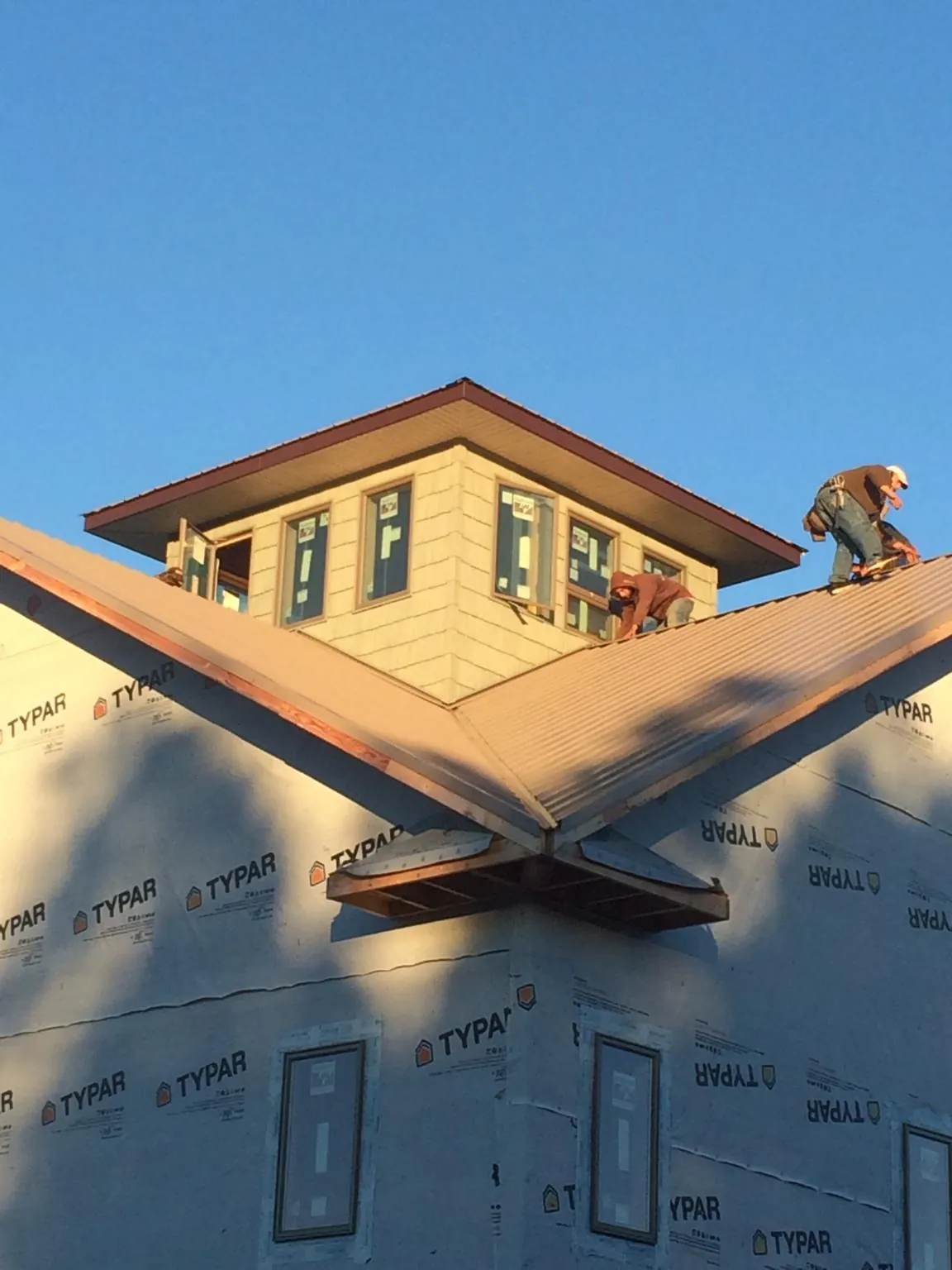 Roofers working around a rooftop cupola on a new metal roof at sunset — Roof Waterproofing in Dripping Springs by Roofing Brothers